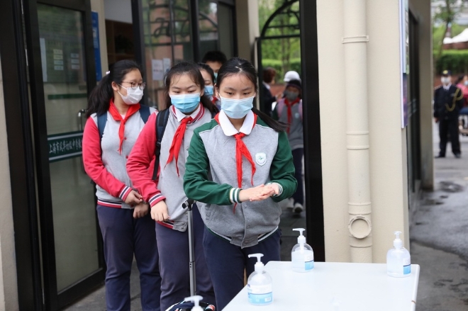 上海市风华初级中学学生进门洗手消毒。