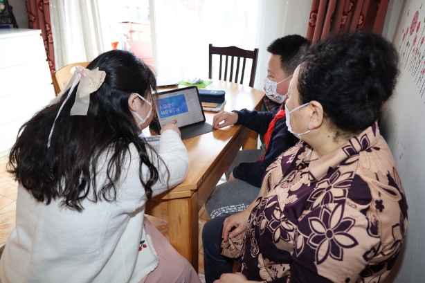 临源居委会社工王艳上门调试电脑，为孩子及奶奶指导上课流程。本文图片均由 上海金山区 提供