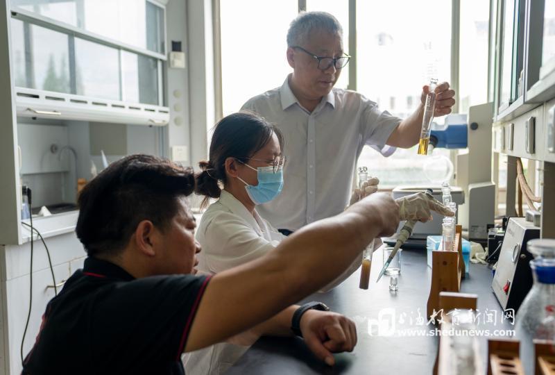 孔娣一边为养殖户做河蟹饲料脂肪含量测定，一边向成永旭汇报数据.jpg